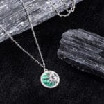"Radiant emerald pendant surrounded by sunburst rays in a bold design"