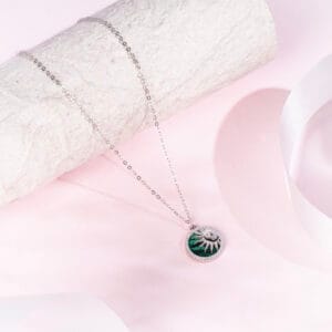 "Radiant emerald pendant surrounded by sunburst rays in a bold design"