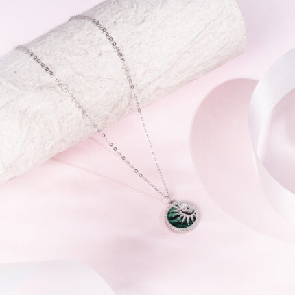 "Radiant emerald pendant surrounded by sunburst rays in a bold design"