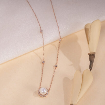 "Rose gold necklace with a crescent moon pendant and single pearl accent"