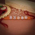 Om Shining Rakhi – Handwoven Thread with Silver & Stone Floral Charms - Image 2