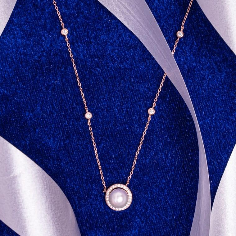 "Rose gold necklace with a crescent moon pendant and single pearl accent"